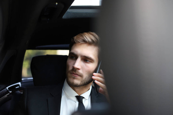 Thoughtful confident businessman talking on the phone while sitting in the car. - Fotoğraf, Görsel