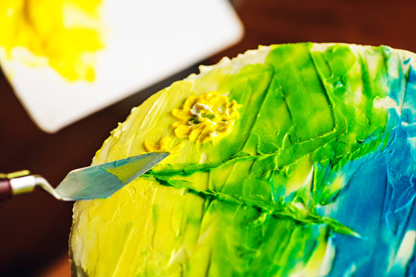 ζαχαροπλάστης διακοσμούν κέικ με πολύχρωμη κρέμα. χειροποίητο κέικ με σχέδιο. - Φωτογραφία, εικόνα