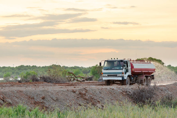 Su kamyonu yeni bir yol inşaatı için su püskürtüyor. - Fotoğraf, Görsel