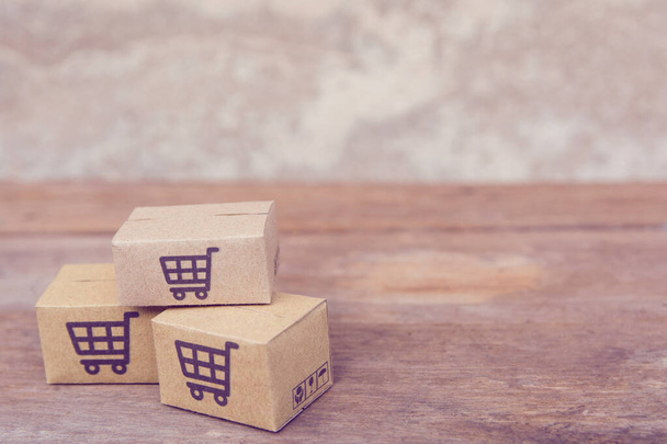 Parcel or Paper cartons with a shopping cart logo on brown wood  - Foto, Imagem