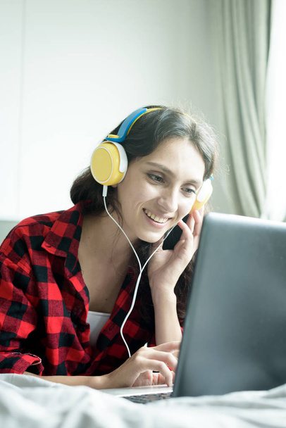 Mooie vrouw werken en luisteren naar muziek op een laptop met  - Foto, afbeelding