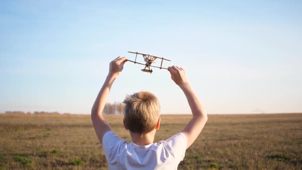 The child runs across the field, holding a plane, simulates flight. Autumn Sunny day. Outdoor entertainment - Footage, Video