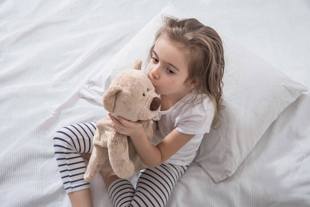 Cute little girl in bed with soft toy. - Valokuva, kuva