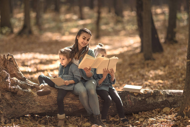 Η μητέρα διαβάζει ένα βιβλίο στα παιδιά στο δάσος.. - Φωτογραφία, εικόνα