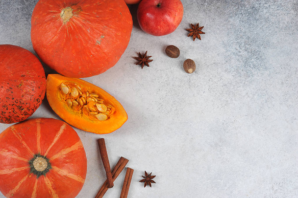 Pumpkins on a light background. The composition is complemented by apples, cinnamon, nutmeg. Free space for text. View from above. - Foto, Imagem