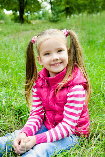 Cute smiling little girl lying in grass on the meadow - Foto, afbeelding