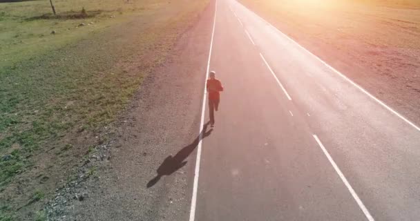 完璧なアスファルト道路でスポーティな男の前で低高度飛行 - 映像、動画