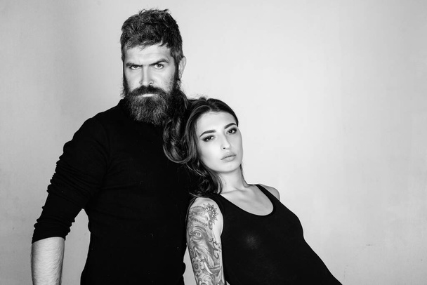 fashion couple. couple in love. brutal bearded man and woman with tattoo. hairdresser and barbershop. tattoo salon. male beard care. hipster man with sexy girl. relationship. serious emotions - Fotoğraf, Görsel