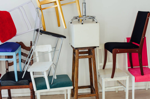 muitas cadeiras diferentes no interior de uma sala branca vazia
 - Foto, Imagem