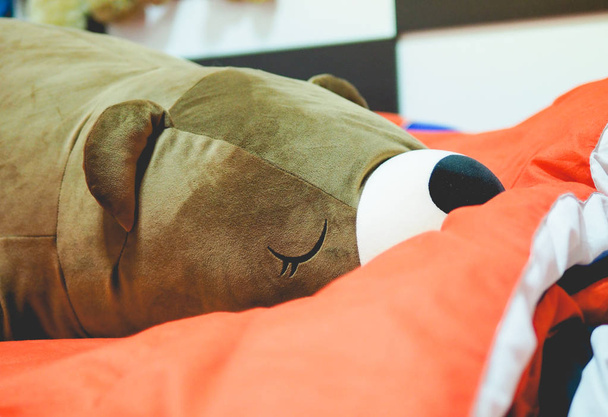 Speelgoedbruine beer slapen op bed, luie beer slapen. - Foto, afbeelding