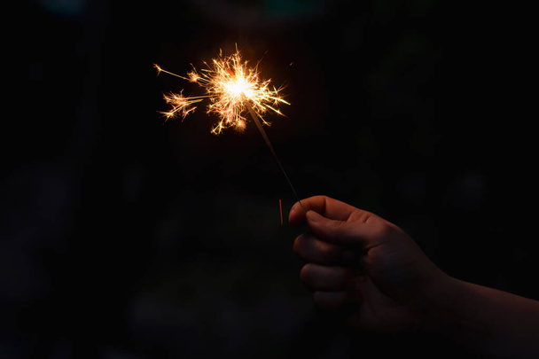 Woman hand holding a burning sparkler - Foto, afbeelding