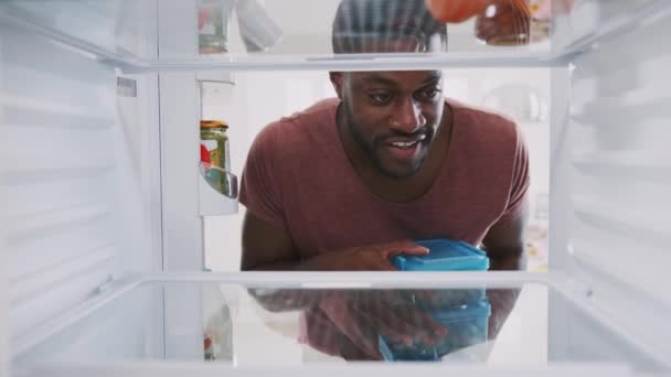 View from inside fridge as man opens door and stacks pre-prepared meals in plastic containers - shot in slow motion - Záběry, video