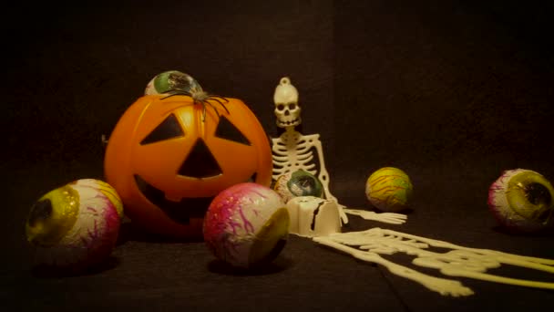 Recursos para una fiesta de Halloween con elementos decorativos espeluznantes y aterradores como una linterna Jack O 'Lantern, esqueletos y caramelos en forma de globos oculares en un sólido fondo negro mate
. - Metraje, vídeo
