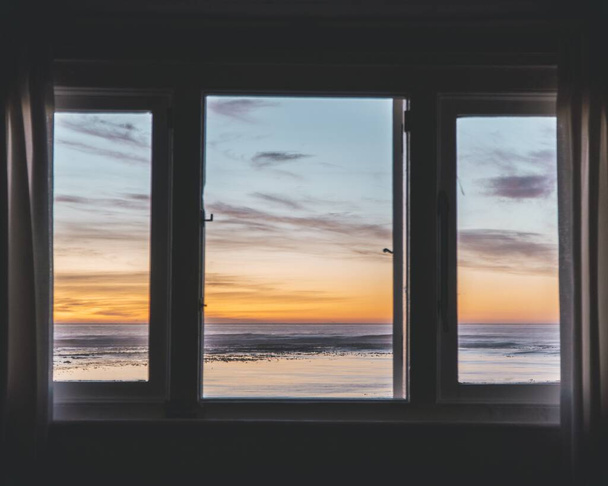 Horizontal shot of a body of water during sunset through a window - 写真・画像