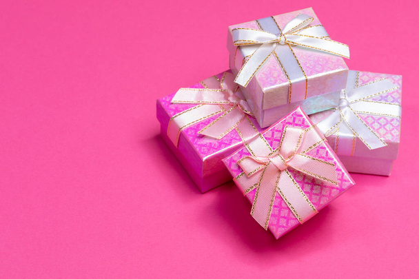 Heap of shiny gift boxes with ribbons and bows on bright pink background with copy space.  - Photo, image