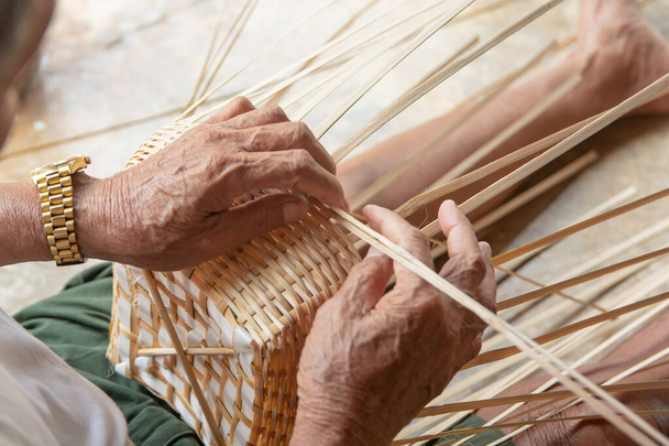Hombre mayor manos tejiendo manualmente bambú
. - Foto, Imagen