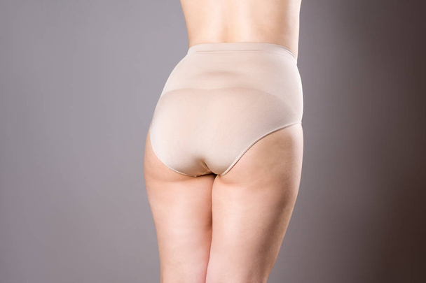 Woman in corrective panties, overweight female body in shapewear on gray background - 写真・画像