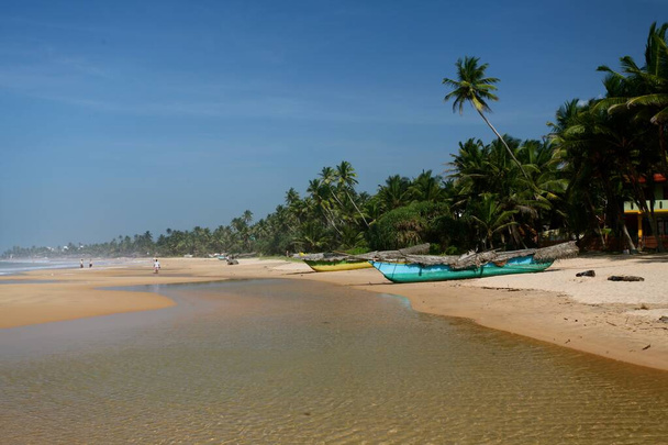 Wide shot of a beautiful beach with boats and palm trees on a sunny day - Fotó, kép