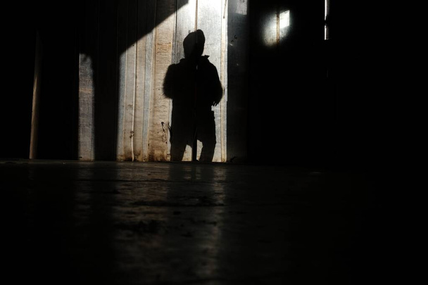 Imagen horizontal de la sombra de una persona en una pared marrón
 - Foto, Imagen