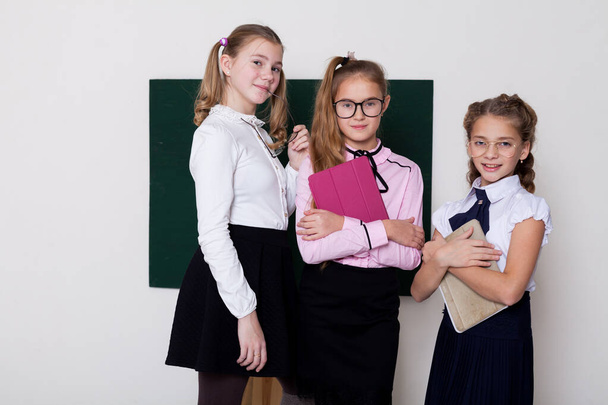 three schoolgirl girls standing at the school board in class - Photo, Image