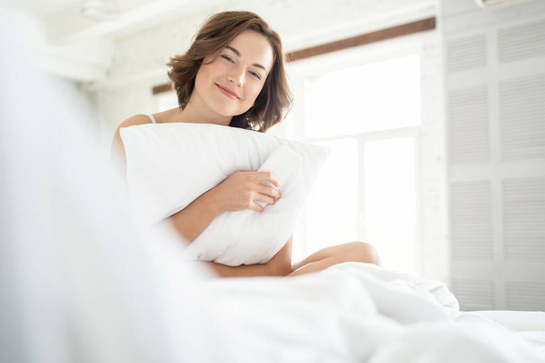 Cute young happy female hugging her pillow - Foto, imagen