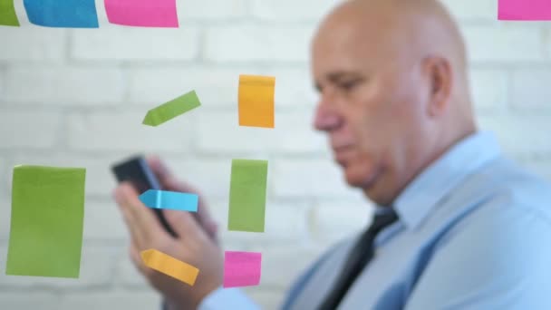 Colored Sticky Notes and Businessman in Blur Text Using Mobile Behind a Window - Filmati, video