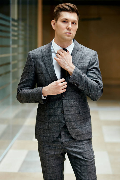 Attractive young man in tuxedo and tie standing outdoors - Foto, Bild