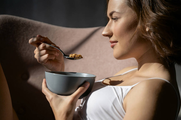 Woman with a bowl of cereal in an armchair - Foto, imagen