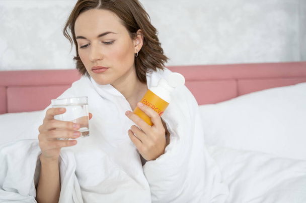 Traurige Frau nimmt Erkältungsmedikamente im Bett - Foto, Bild