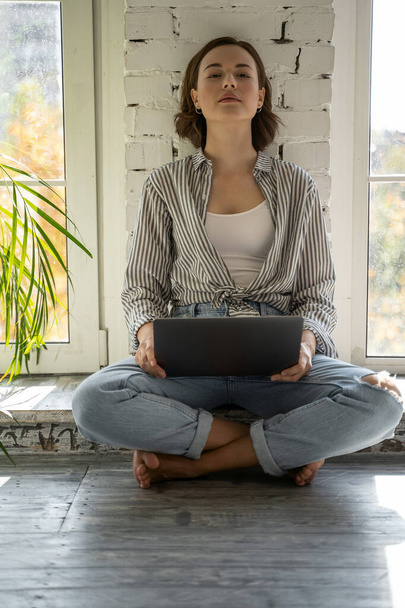 Mujer joven y tranquila sentada con un portátil
 - Foto, imagen