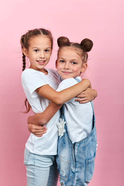 cute two friends hugging in the studio with pink wall - Fotoğraf, Görsel