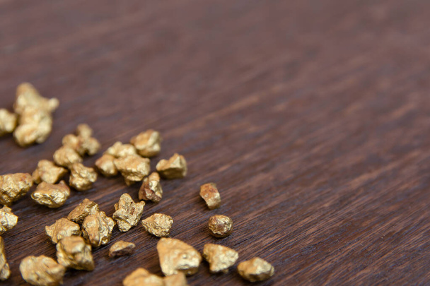 mound of gold nugget on dark wood background - Fotoğraf, Görsel