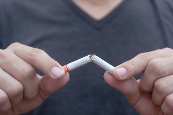 Sigarayı bırak, erkek eli kesiciyle sigarayı kırıyor. - Fotoğraf, Görsel