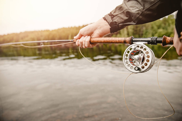 Carrete de pescador de cuerda con varilla de pesca con mosca en el río
 - Foto, imagen