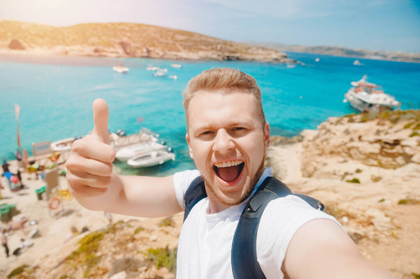 mężczyzna turysta okulary robienie selfie zdjęcie na plaży Blue Lagoon Comino Malta woda Morze Śródziemne - Zdjęcie, obraz
