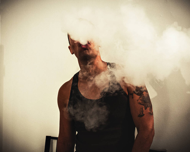 Mies joka polttaa sähkösavuketta, höyryä
 - Valokuva, kuva