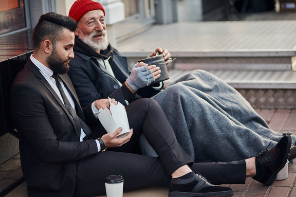 Senior caucasian beggar male telling story about life to businessman - Фото, зображення