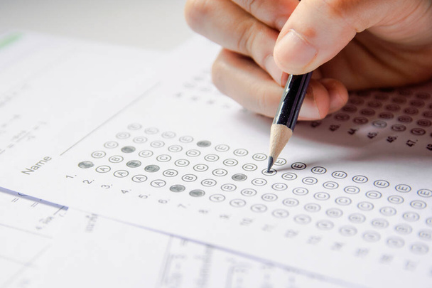 Студентська рука тримає олівець, пишучи вибраний вибір на відповідь s
 - Фото, зображення