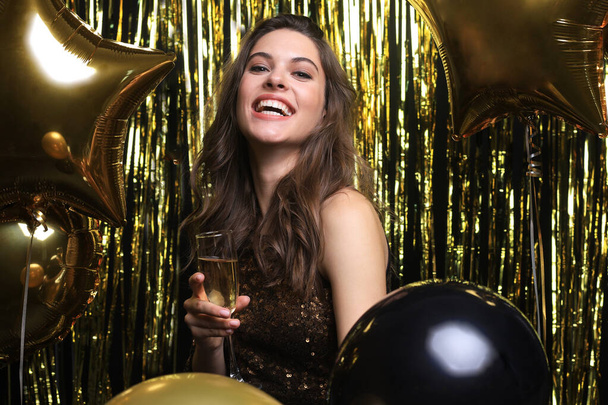 Cheerful woman with balloons laughing on gold background. - Foto, Imagen