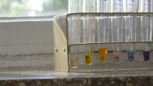 Farbiges flüssiges Wasser in medizinischen Reagenzgläsern im Labor auf altem Fenster mit Marmorfensterbank. - Filmmaterial, Video