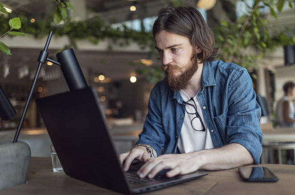 Young Man Working by Laptop in a Loft Cafe - Zdjęcie, obraz