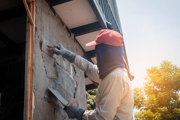 Construction workers plastering building wall using cement plast - Valokuva, kuva