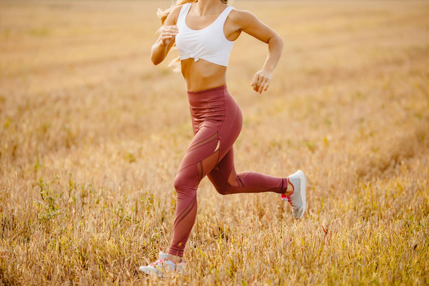 Молода жінка блондинка біжить у спортивному одязі працює на полі поза парком
 - Фото, зображення