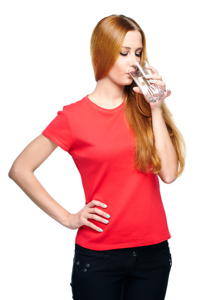 Una joven atractiva con una camisa roja. Beber agua mineral
. - Foto, Imagen