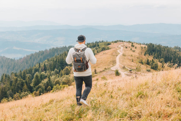 man with backpack hiking by autumn mountains - Photo, Image