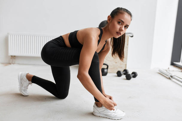 Attractive girl athlete tying shoelashes, prepare for workout - Valokuva, kuva