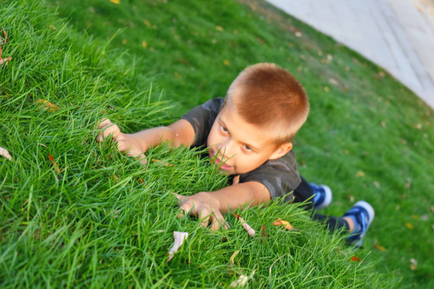 The boy climbs on the grass. Funny children's games in the grass - Foto, Imagen