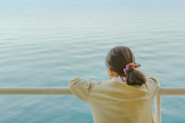 Aasialainen nuori tyttö seisoo lautalla rentoutumiseen ja katso merta ja saarta
 - Valokuva, kuva
