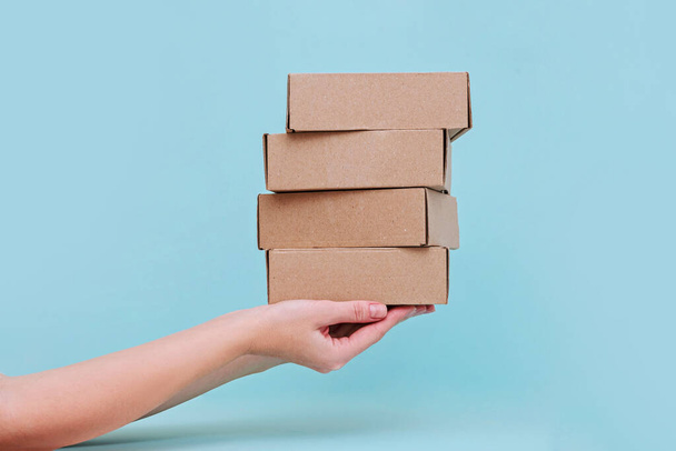 Woman's hands holding boxes stacked on blue pastel background. Mock up. - Photo, Image