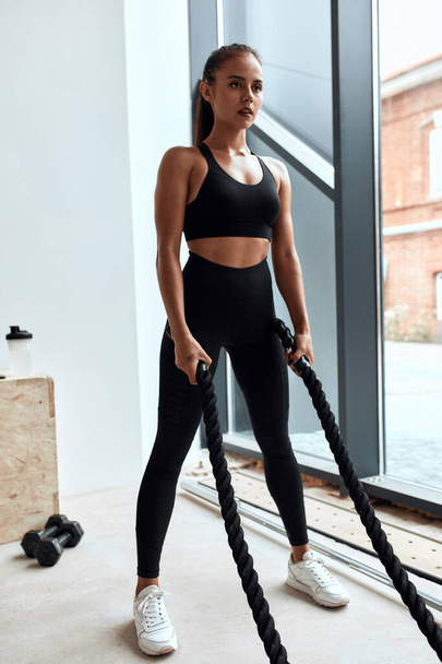Beautiful woman use training ropes in gym - Фото, изображение